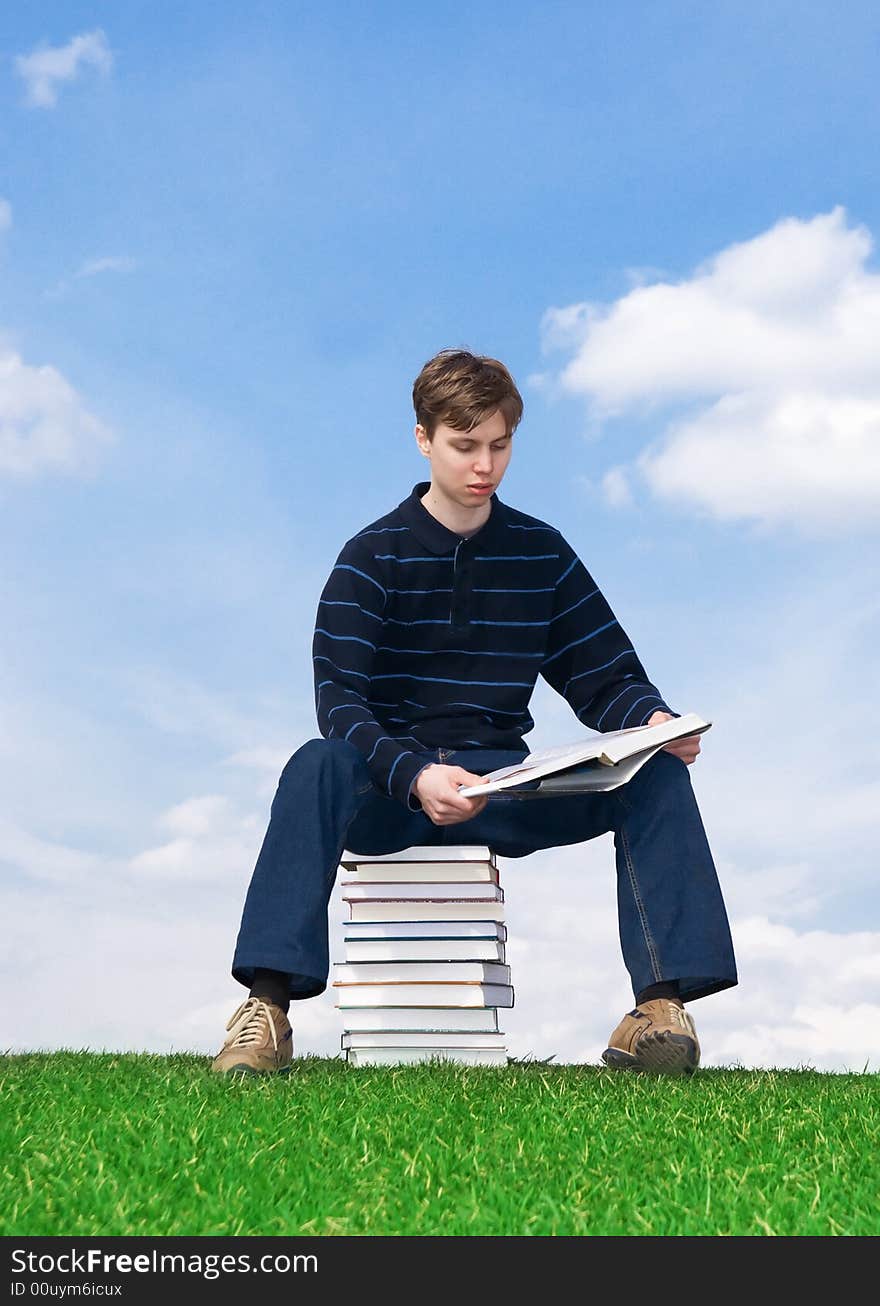 The young student with the books on a background of the blue sky