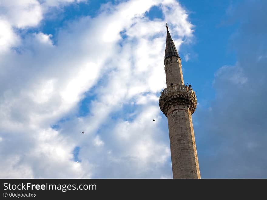 Single mosque minaret under the blue and cloudy sky