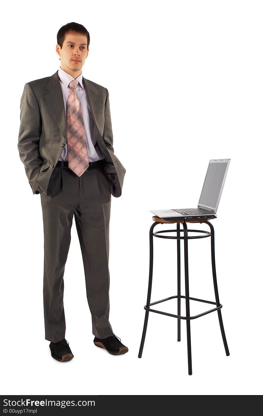 Young businessman stands near laptop. Young businessman stands near laptop