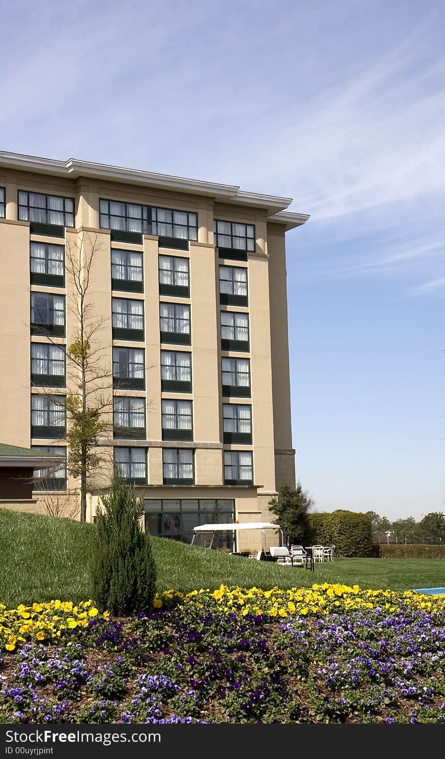 A nice hotel with landscaped flower beds against a blue sky and clouds. A nice hotel with landscaped flower beds against a blue sky and clouds