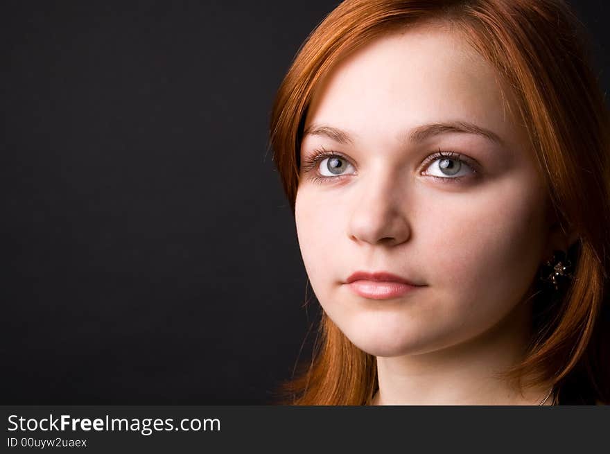 The charming young girl in studio on black background