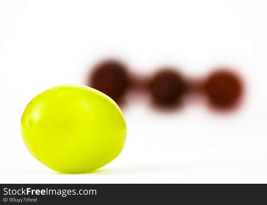 Green Grape in front of Three red grapes