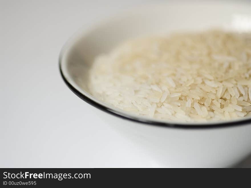 White bowl with rice on a white surface. White bowl with rice on a white surface