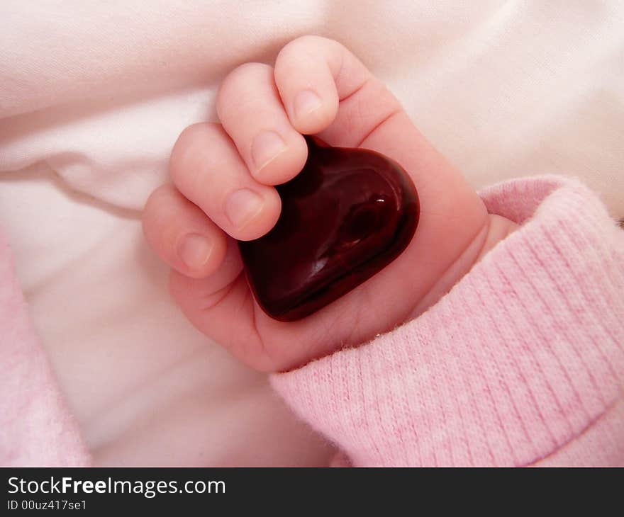 Little girl's hand with red glass heart