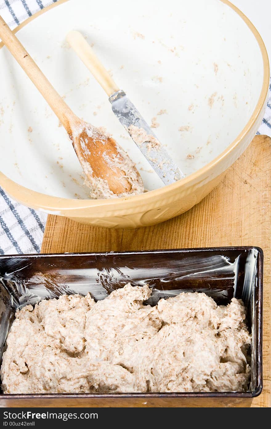 Fresh dough in a baking tin and an empty bowl. Fresh dough in a baking tin and an empty bowl