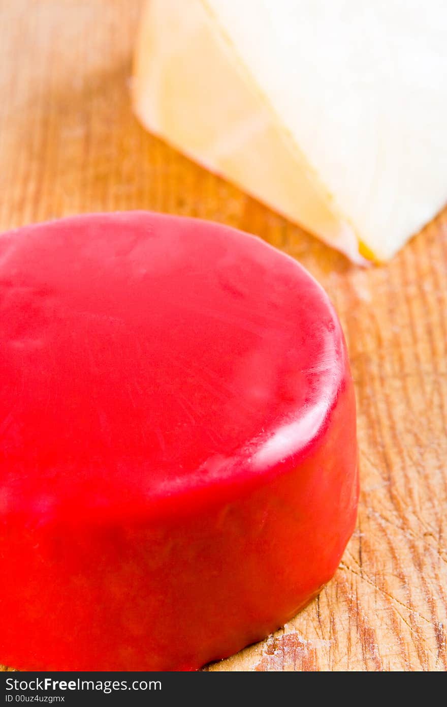 Red cheese and a slice of gounda on a wooden board