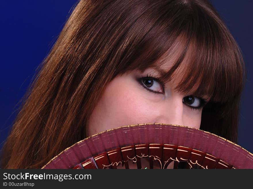 Close up portrait of cute young lady fanning herself with decorative spanish fan. Close up portrait of cute young lady fanning herself with decorative spanish fan