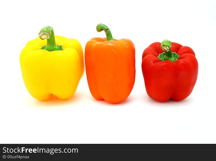 Fresh orange, yellow and red  peppers over a white surface