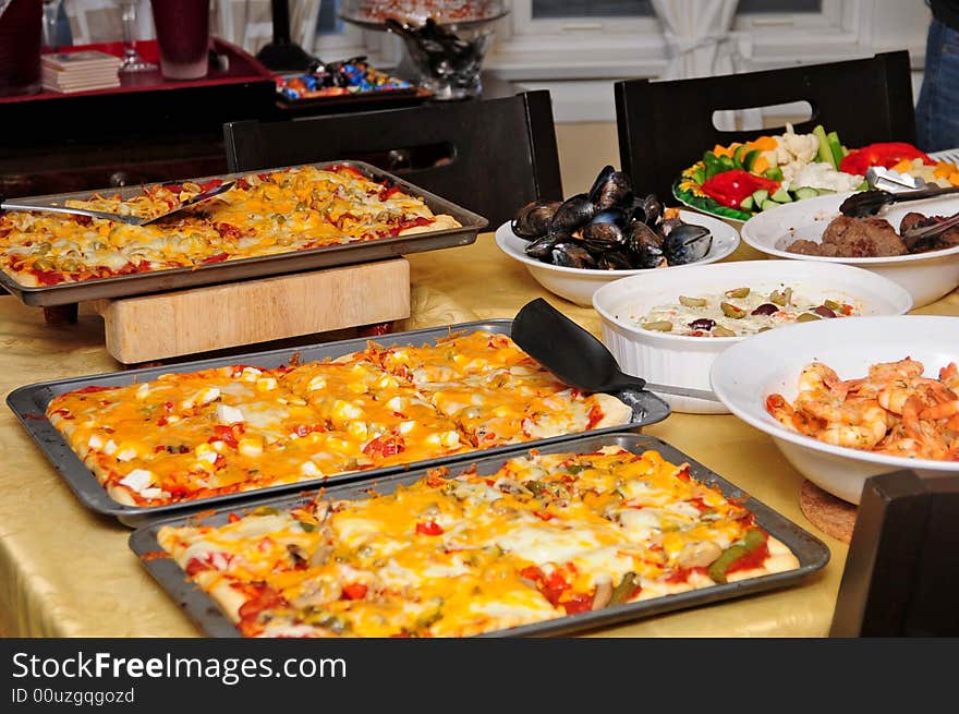 A full table with salad, shrimp, veggies and pizza. A full table with salad, shrimp, veggies and pizza