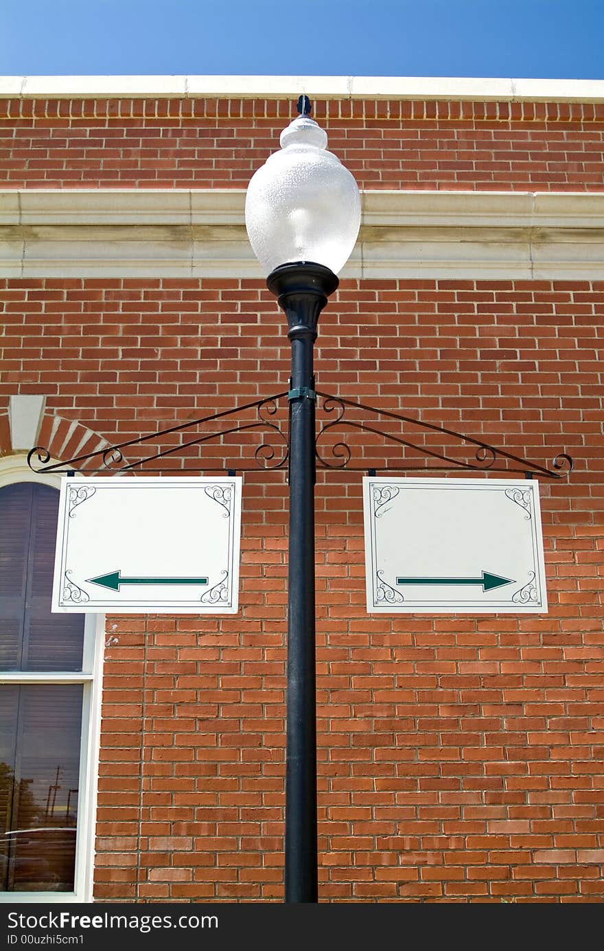 A lamp post with two signs hanging from it with nothing but arrows on them. A lamp post with two signs hanging from it with nothing but arrows on them.