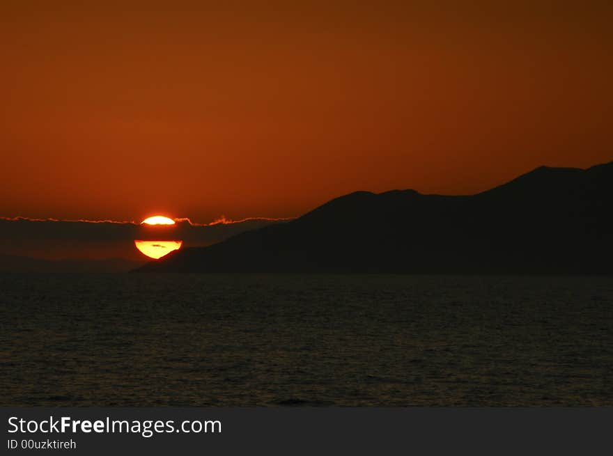 Sunset over Galapagos with the cloud spliting the sun showing two tones of yellow