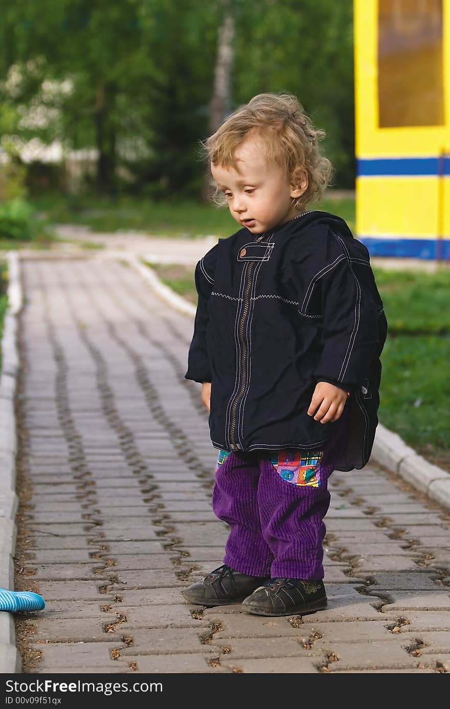 Small curly boy stand on a roadway