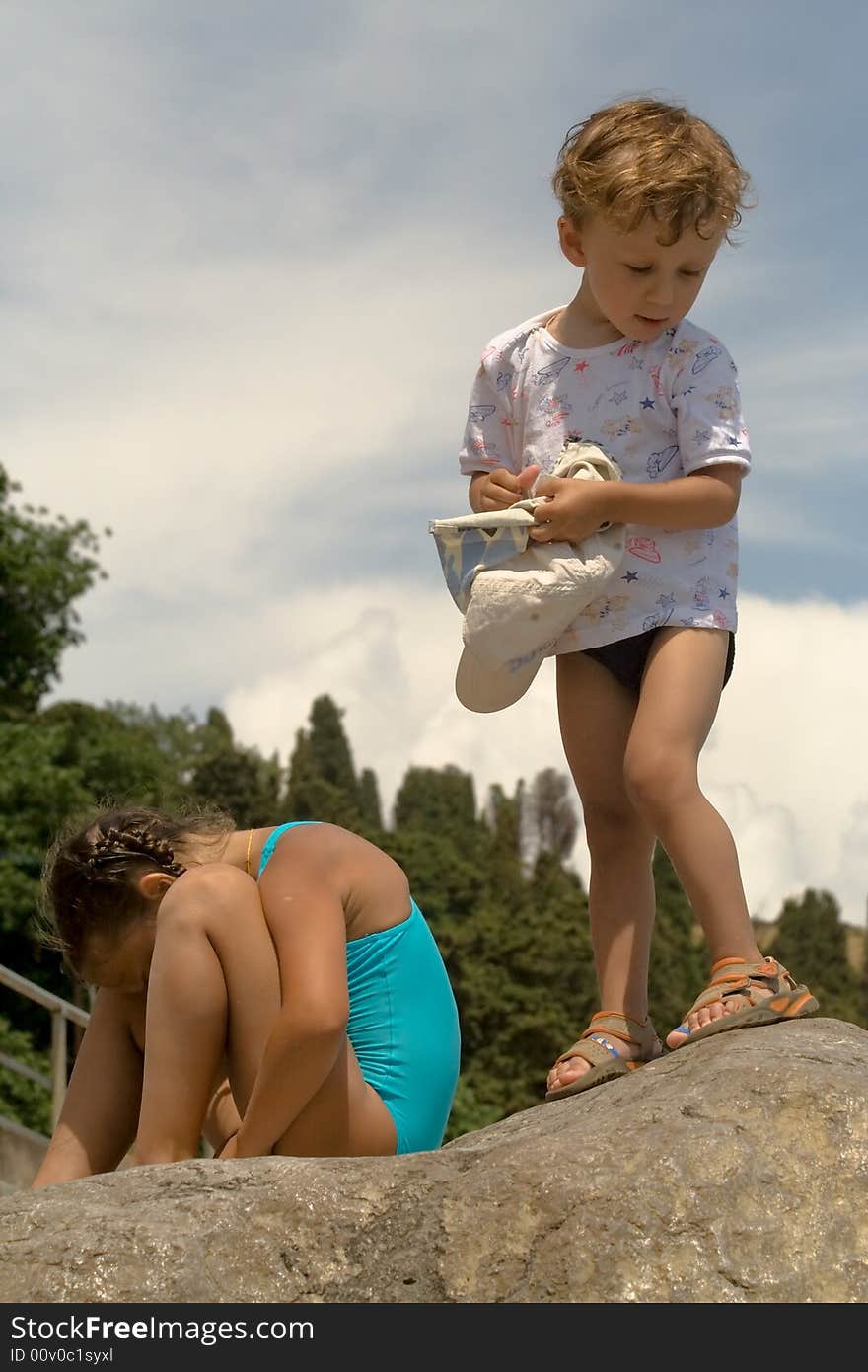 A little boy in a sport shirt stands on a stone on a background mountains and gets on the hip a service cap. A little boy in a sport shirt stands on a stone on a background mountains and gets on the hip a service cap