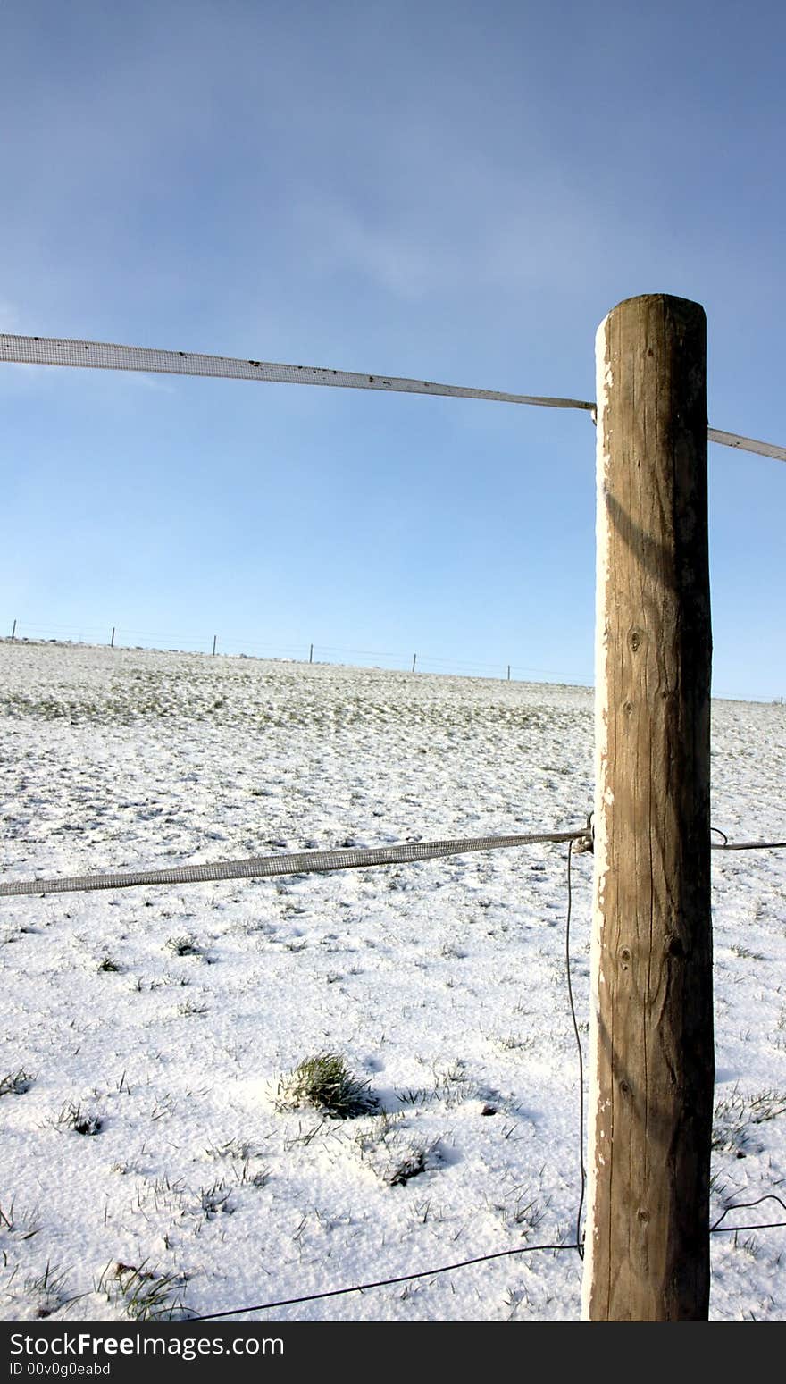 A post and a segment of fence on a meadow in winter. A post and a segment of fence on a meadow in winter