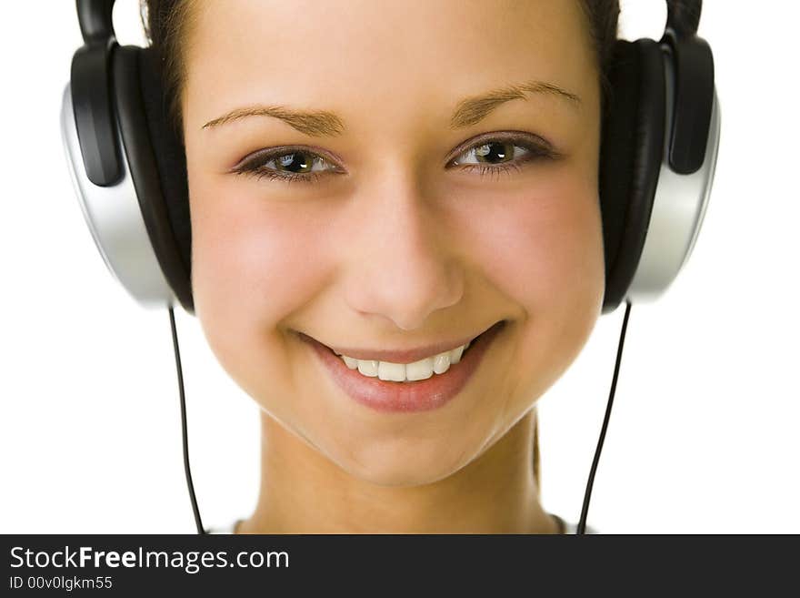 Young woman listening to music by headset. Looking at camera and smiling. Closeup on face. Front view. White background. Young woman listening to music by headset. Looking at camera and smiling. Closeup on face. Front view. White background.