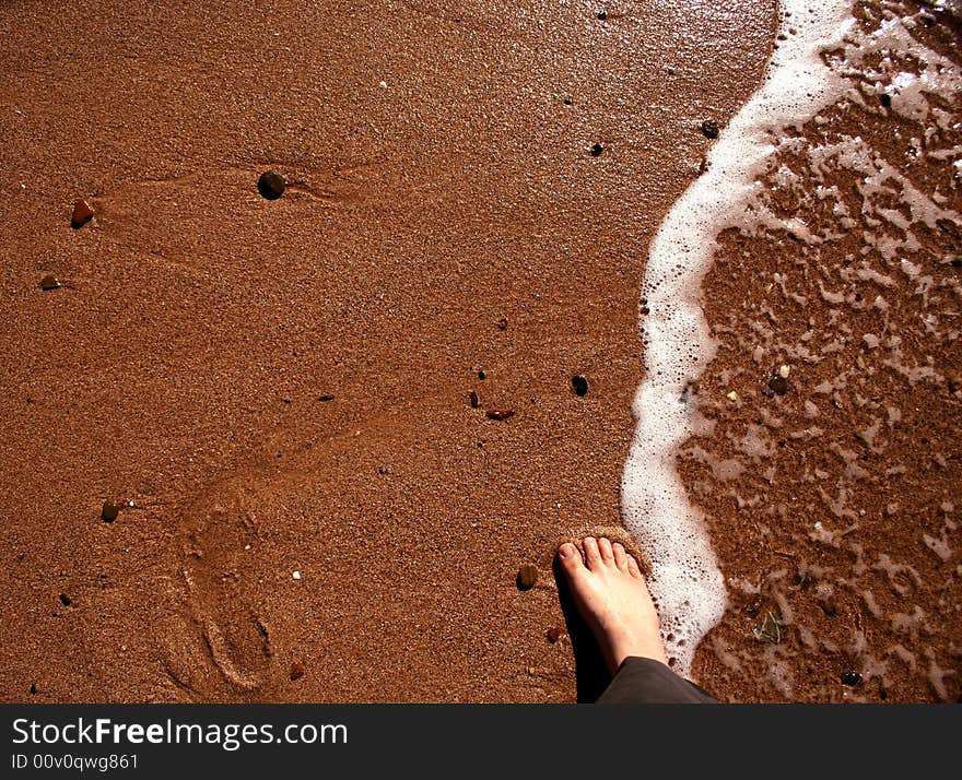 A foot and an empty foot track on a beach. A foot and an empty foot track on a beach.