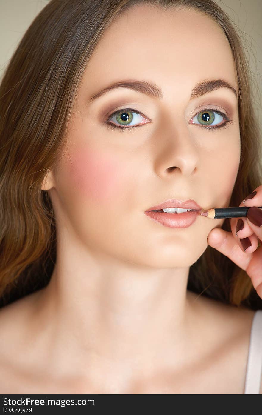 Young woman with green eyes and long brown hair getting her make-up done by a make-up artist � lip liner application. Young woman with green eyes and long brown hair getting her make-up done by a make-up artist � lip liner application