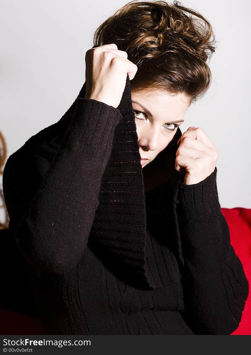 Beautiful woman wearing a black sweater pulling her collar around her face