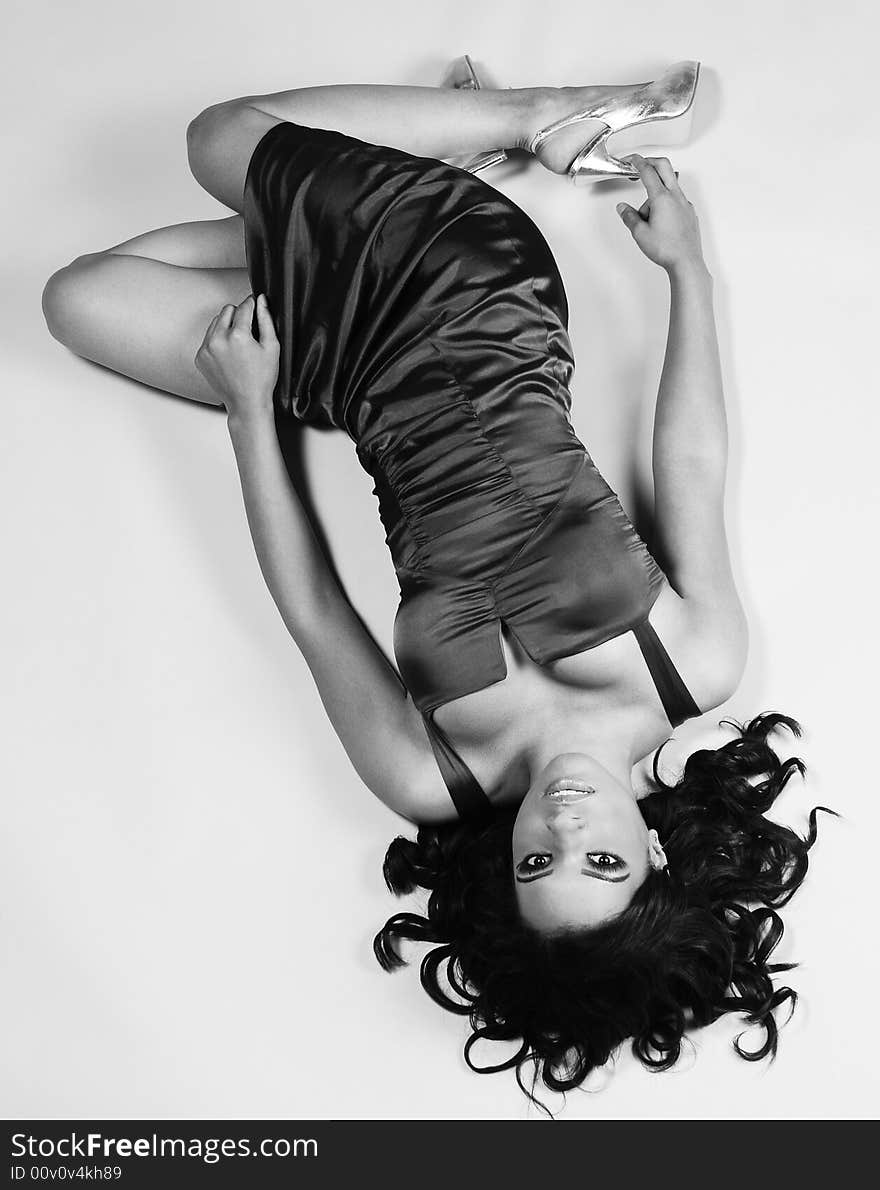 Young woman wearing a cocktail dress lying on her back looking upwards. Young woman wearing a cocktail dress lying on her back looking upwards