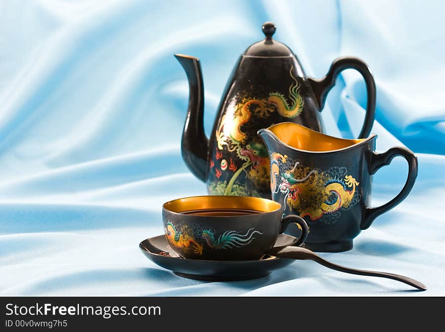 Teapot and cup filled with black tea. Teapot and cup filled with black tea