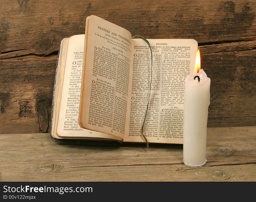 Old prayer book and candle agapnst a background of rustic wood