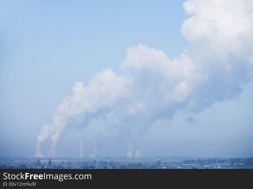 Power station bellowing emitting smoke from chimneys