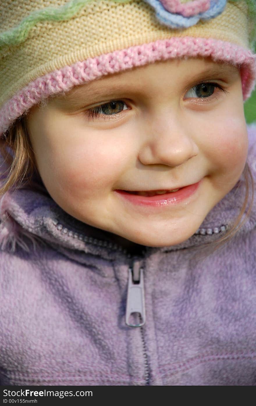 Little pretty girl wearing a hat is smiling outdoors. Little pretty girl wearing a hat is smiling outdoors