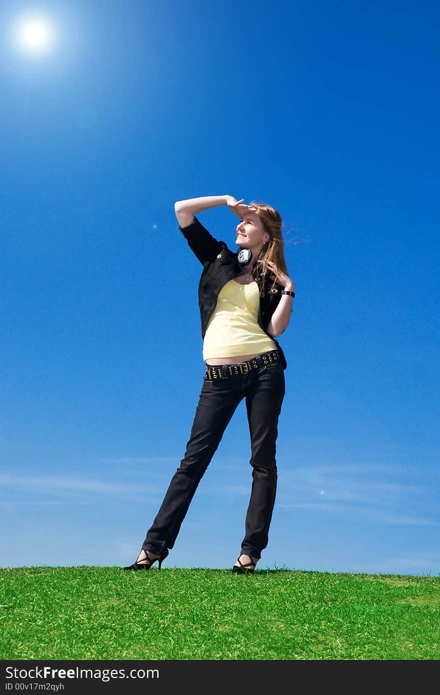 The young attractive girl with headphones on a background of the blue sky