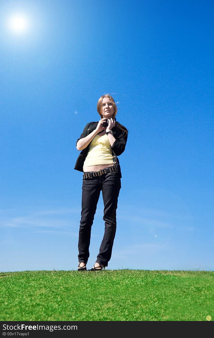 The young attractive girl with headphones on a background of the blue sky