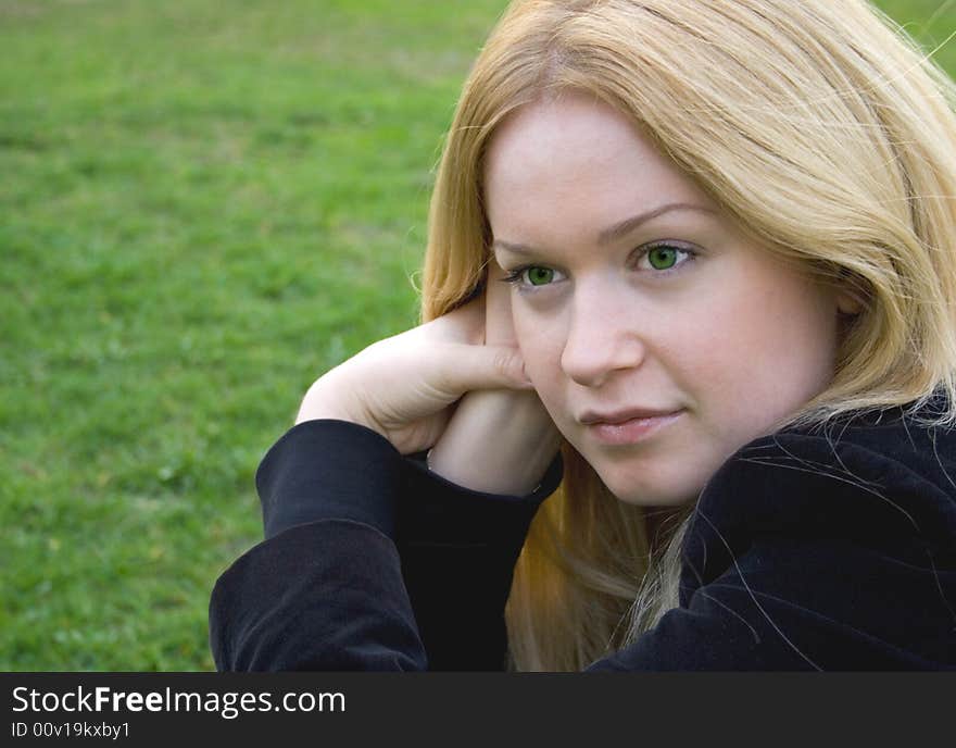 Pretty young blonde over green grass background. Pretty young blonde over green grass background