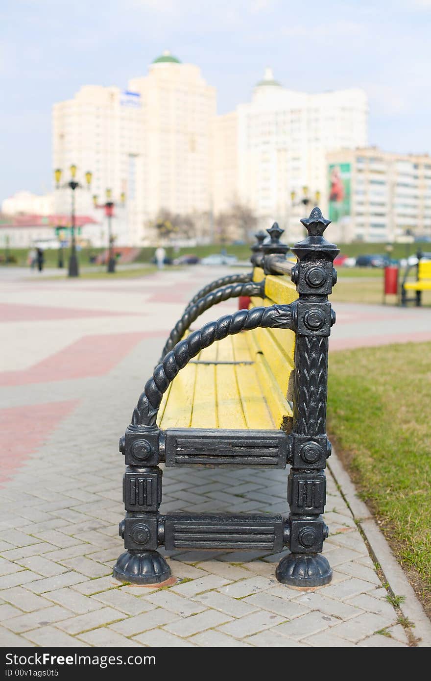 Park bench with city skyline behind. Focus on bench