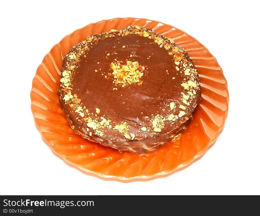 Home made round chocolate cake on the orange plate. It's made of sweet wafers smeared with cacao cream. 
Top is covered by chocolate icing with walnut's pieces and waffle crumbs. Home made round chocolate cake on the orange plate. It's made of sweet wafers smeared with cacao cream. 
Top is covered by chocolate icing with walnut's pieces and waffle crumbs.