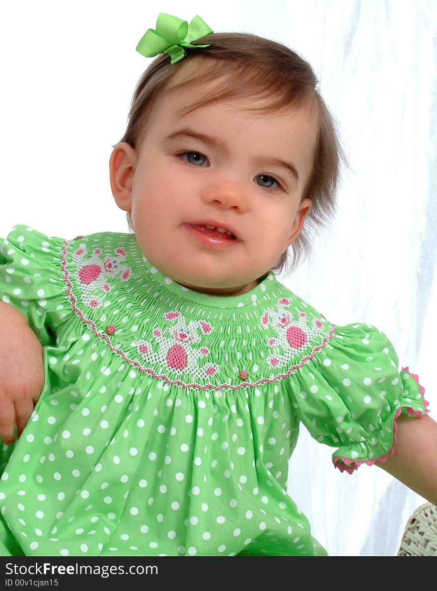 Baby girl in green sitting in front of white background