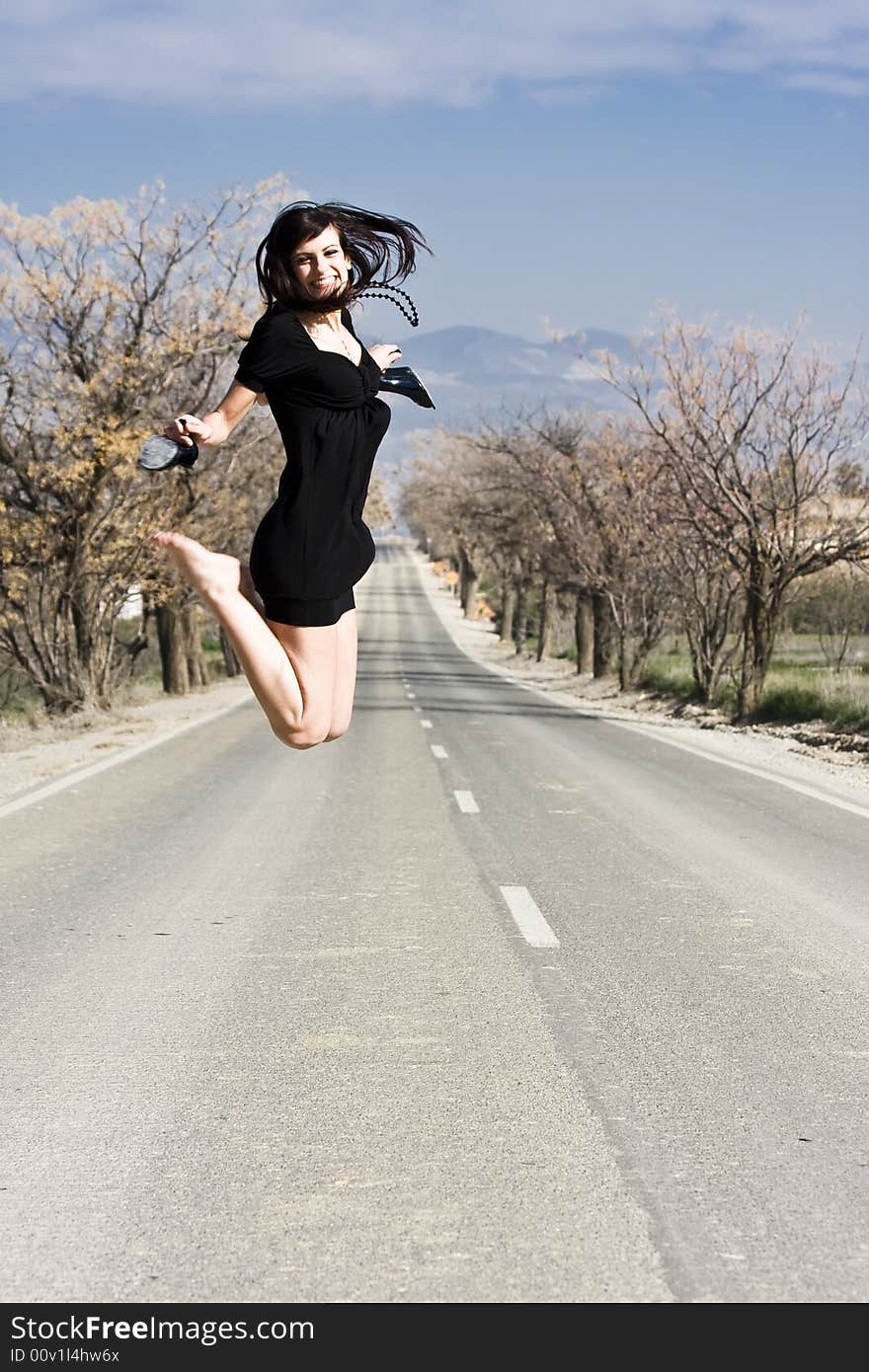 Happy girl jumping in the middle of the road