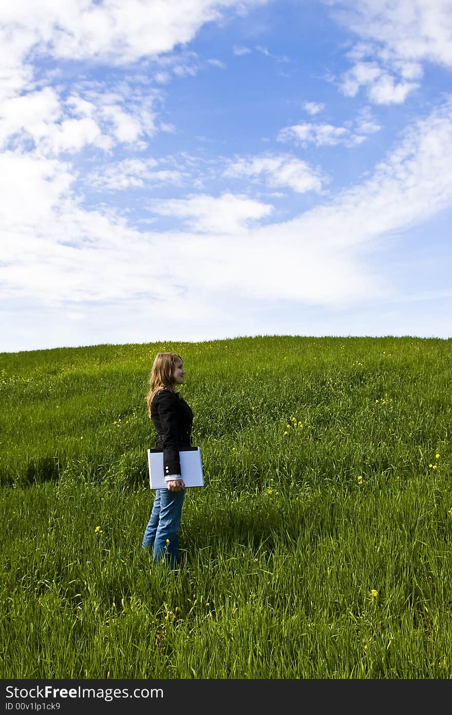 Young woman with laptop in meadow