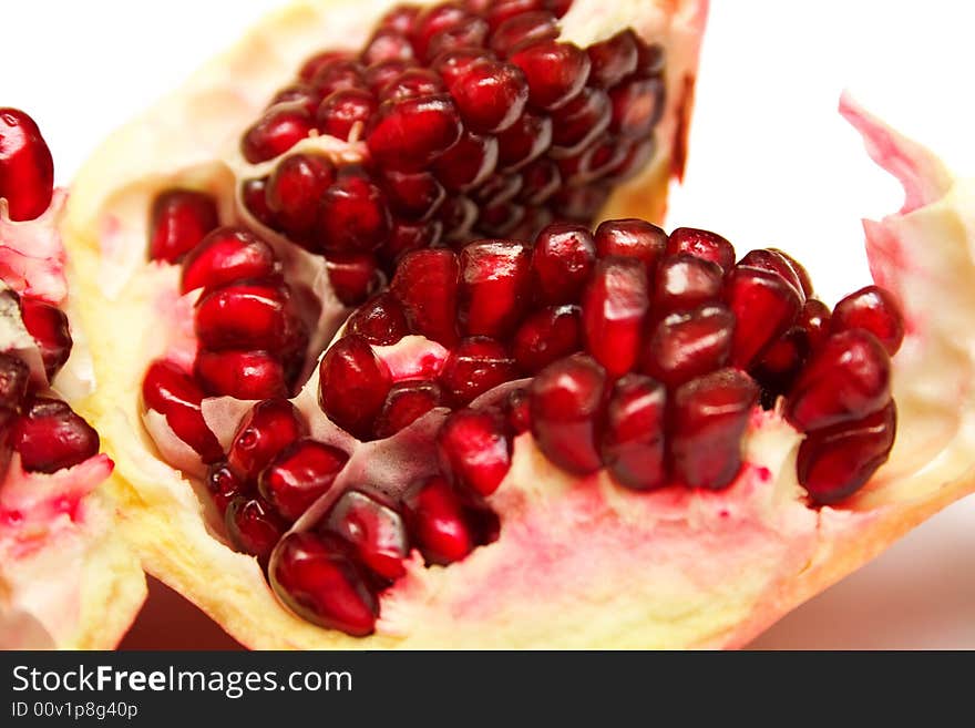 The pomegranate divided into parts on white. The juicy fruit containing set of vitamins, useful to a human body.