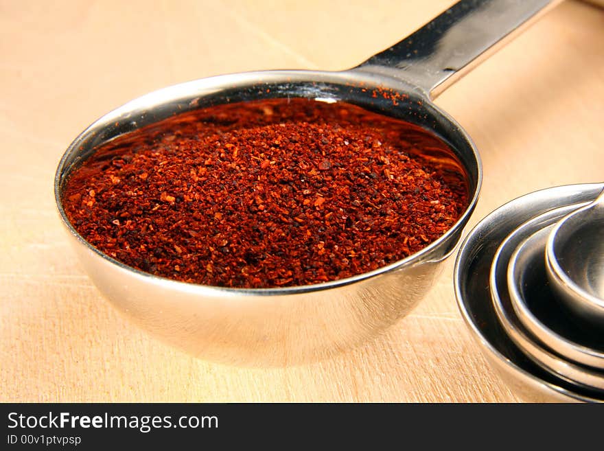 Chili powder in measuring spoon on cutting board. Chili powder in measuring spoon on cutting board