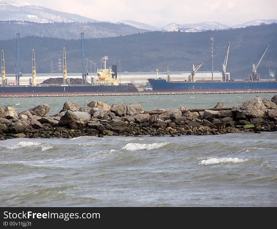 Cargo ships in the port in Italy vs. the nature, beach; snow in the surrounding hills, wintertime; 

Industry polluting the nature concept. Cargo ships in the port in Italy vs. the nature, beach; snow in the surrounding hills, wintertime; 

Industry polluting the nature concept