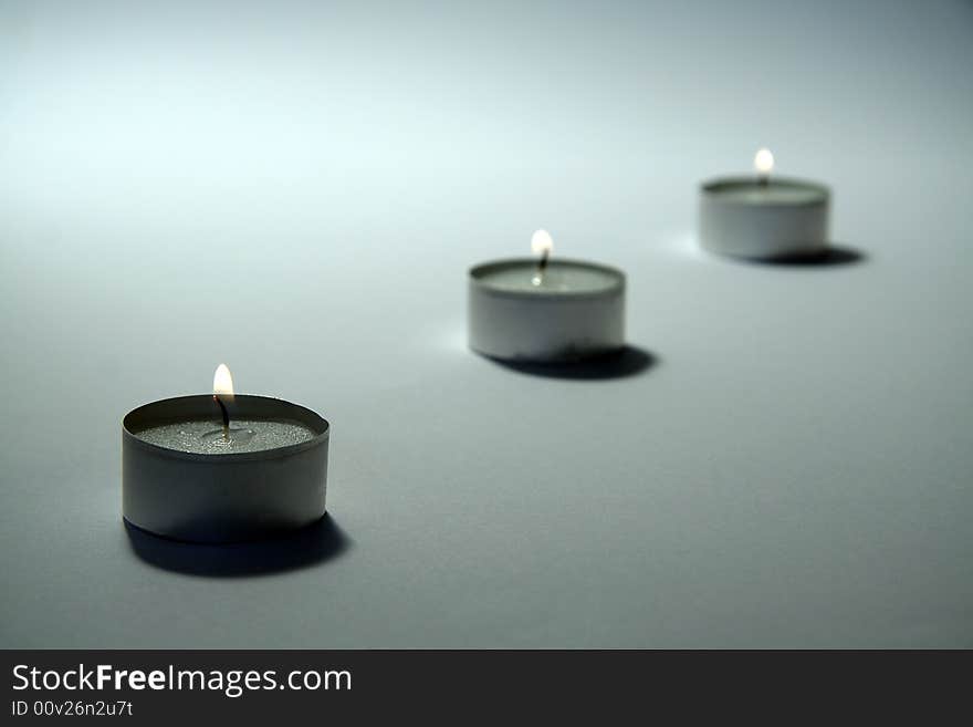 Three small candles on white background, distance blur. Three small candles on white background, distance blur