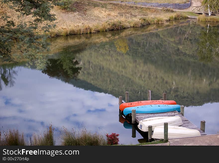 Landscape reflected on still lake with canoes. Landscape reflected on still lake with canoes