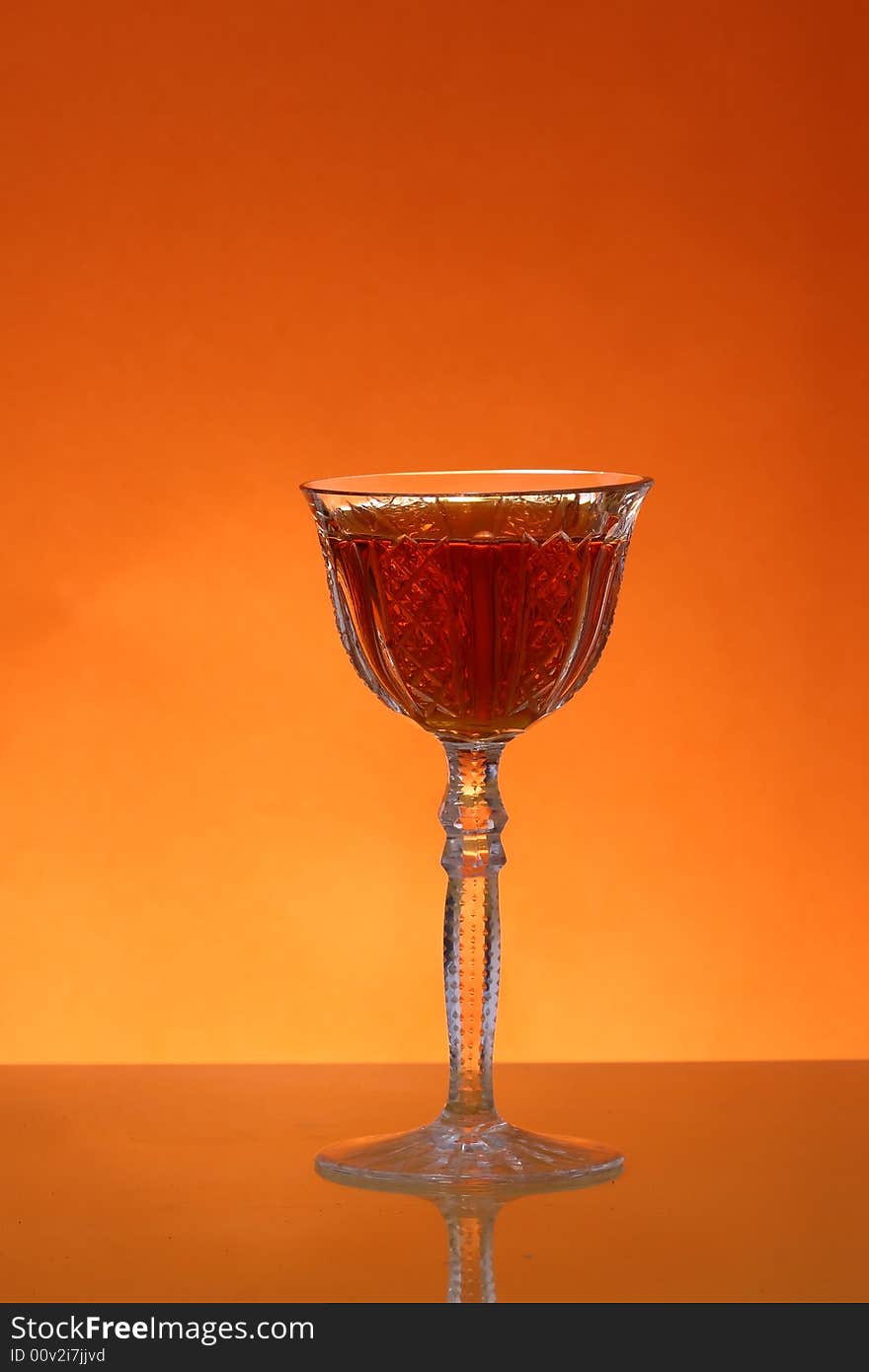 Glass of liqueur over orange background