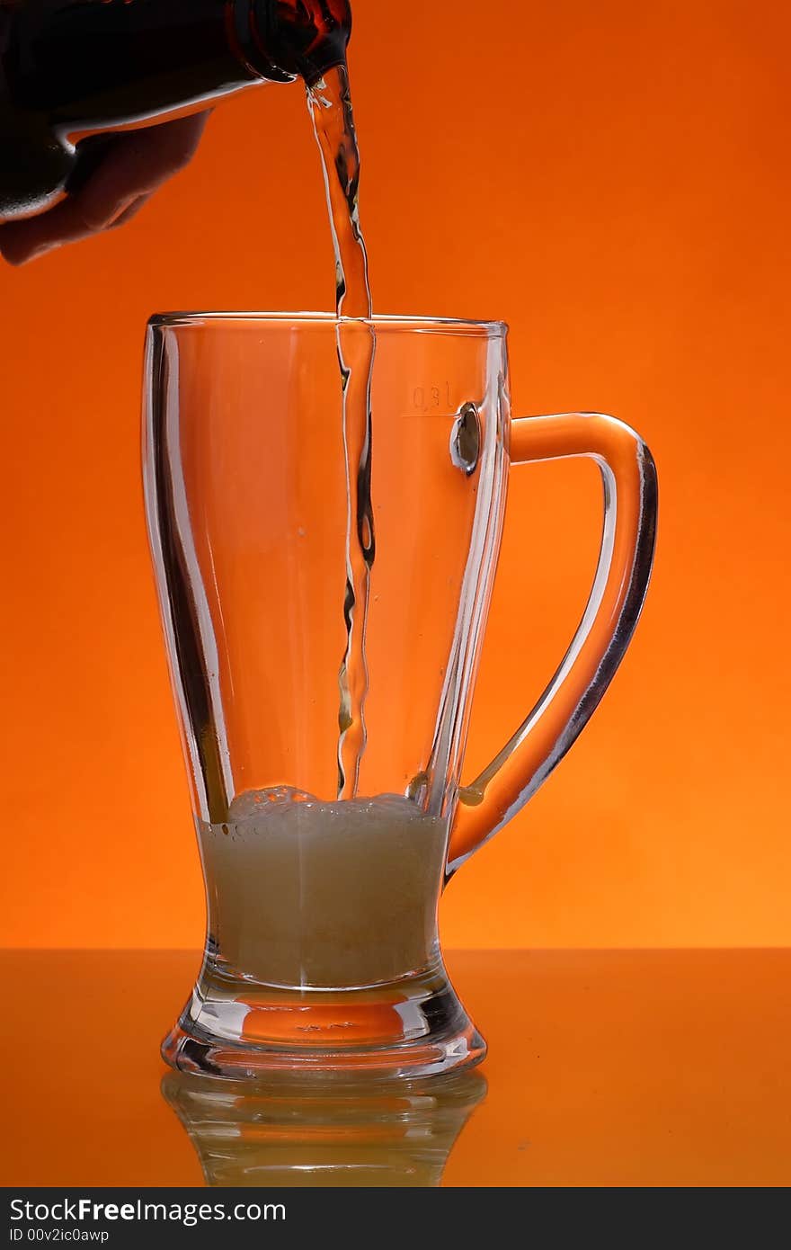 Pouring beer into gass over orange background