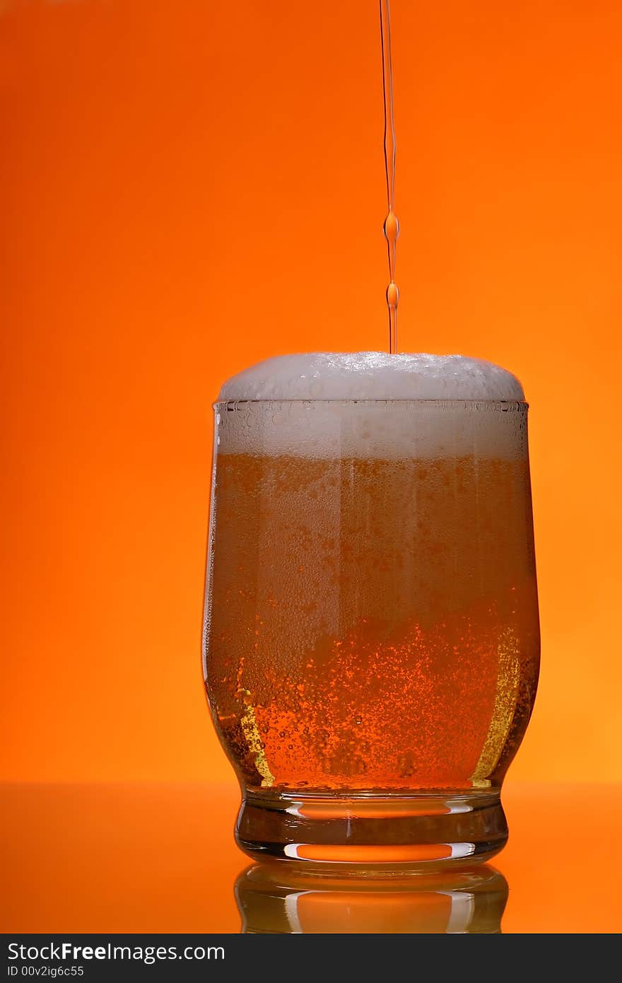 Pouring beer into the gass over orange background