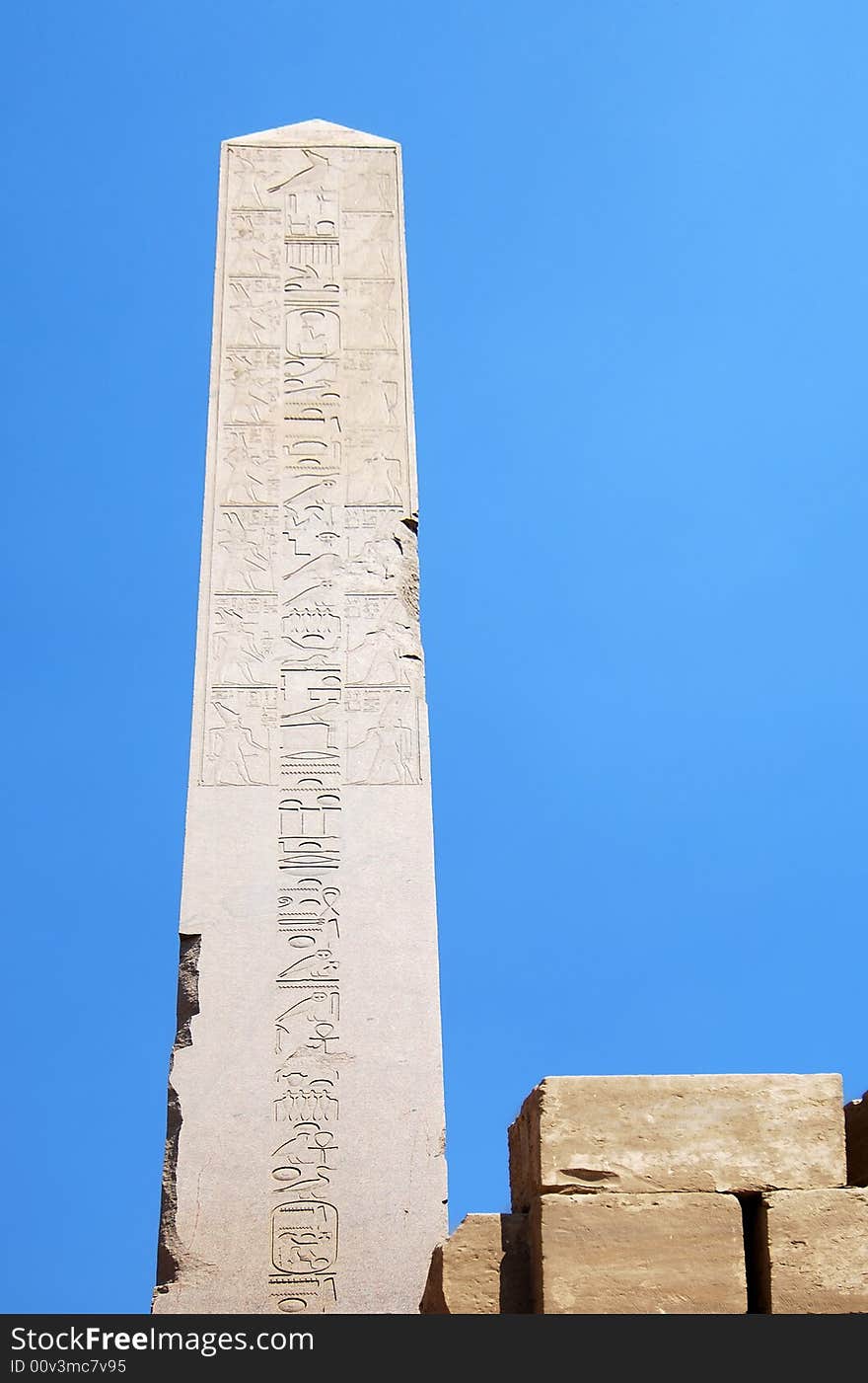 Egyptian obelisk with hieroglyphs on the blue sky