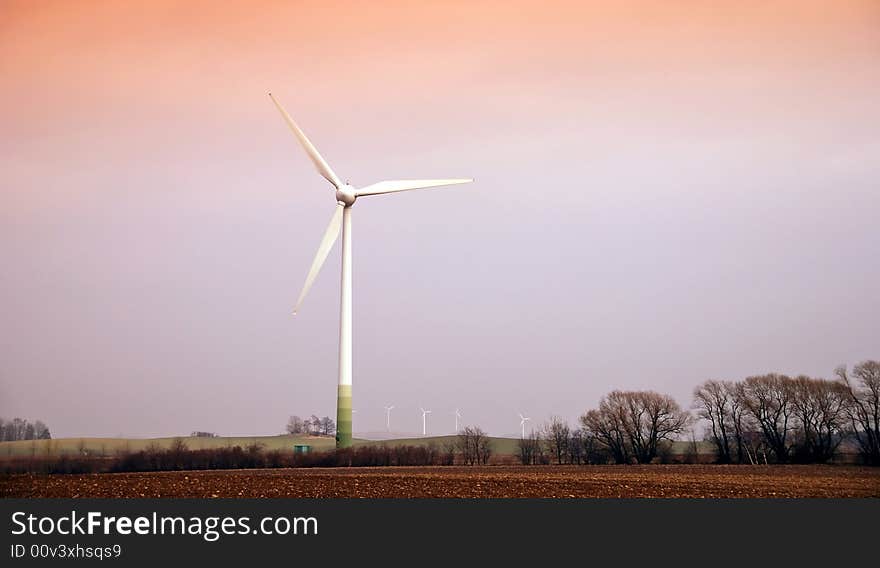 Wind turbines in movement during the sunset in the fields