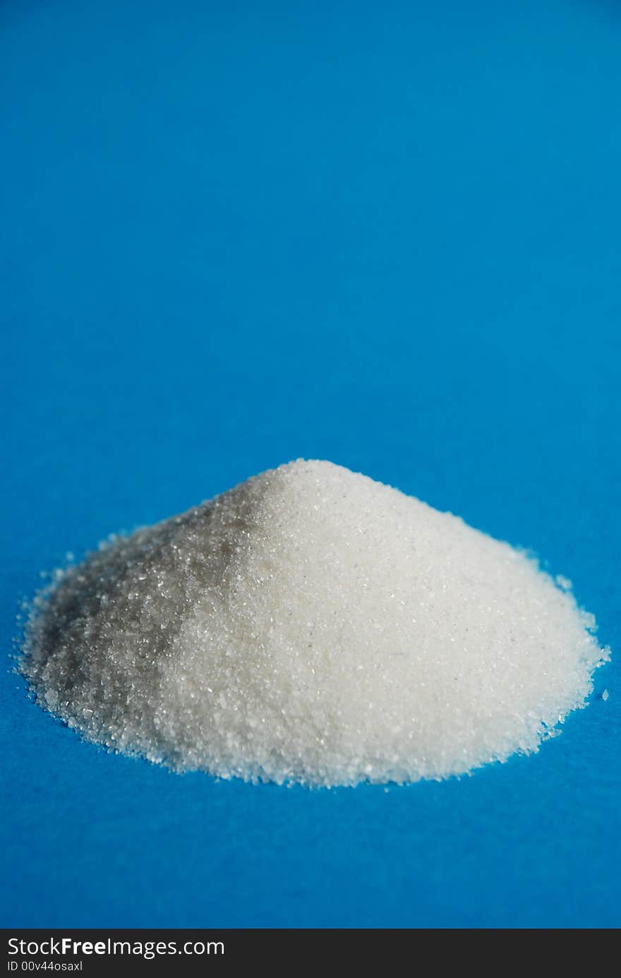 Heap of white sugar on a blue background