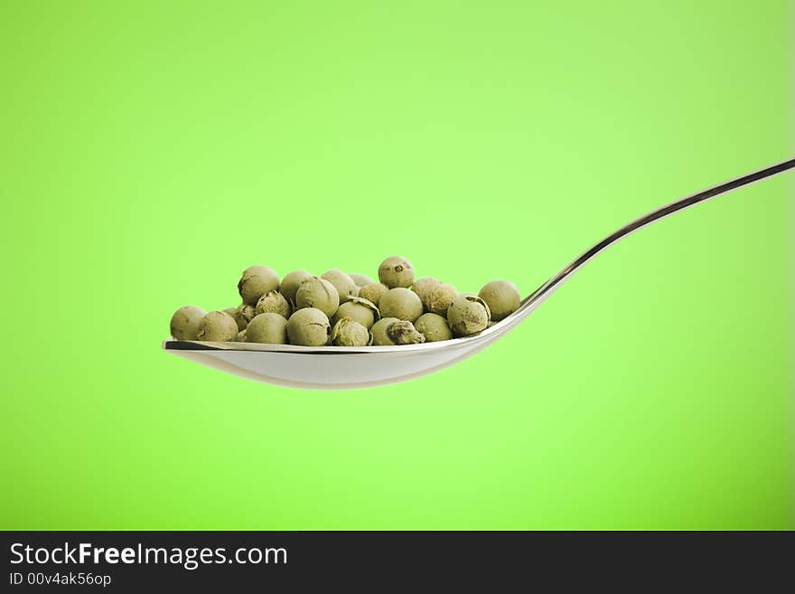 Metal spoon filled with dried green peppers. Metal spoon filled with dried green peppers