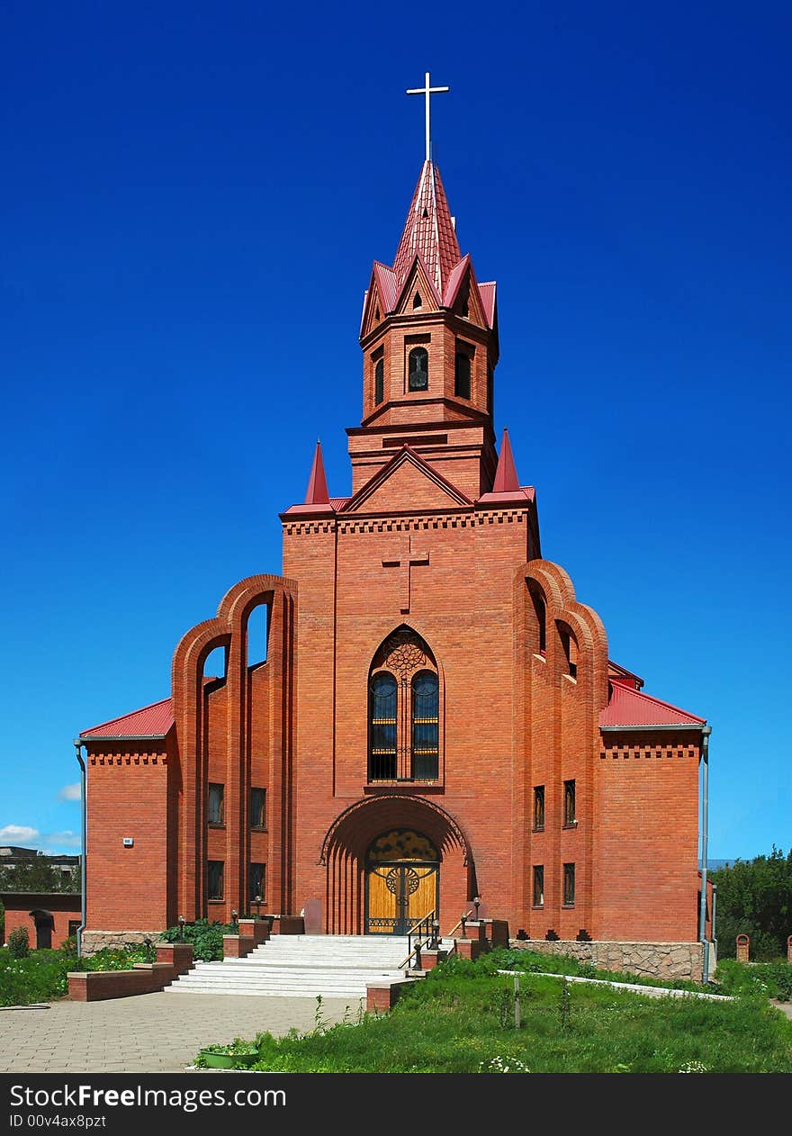 Roman catholic church on turn blue sky, green lawn