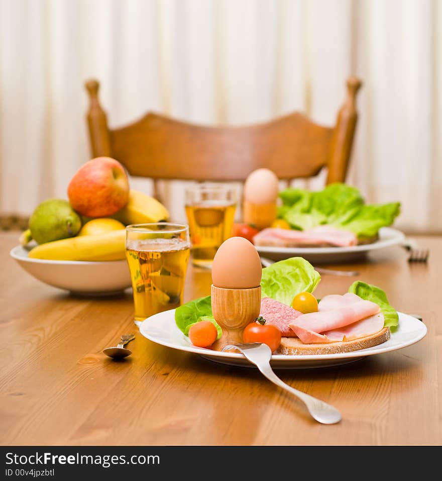 Table served with snacks. Fruits, vegetables, bread, egg, ham etc. Focus on the front egg, shallow depth of field. Table served with snacks. Fruits, vegetables, bread, egg, ham etc. Focus on the front egg, shallow depth of field.