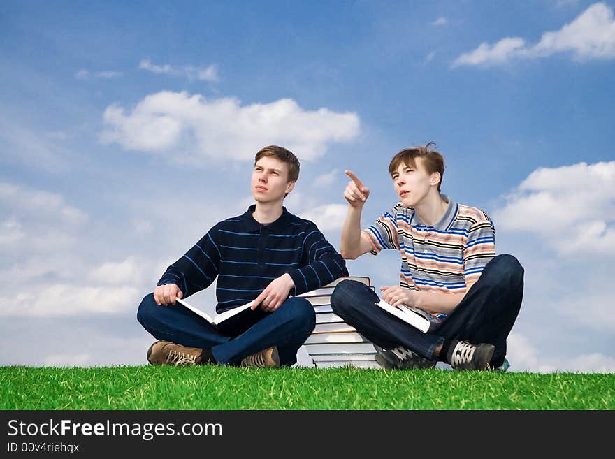 The two students with the book on a background of the blue sky